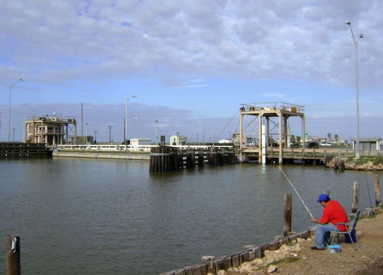 man fishing on the river by a wharf