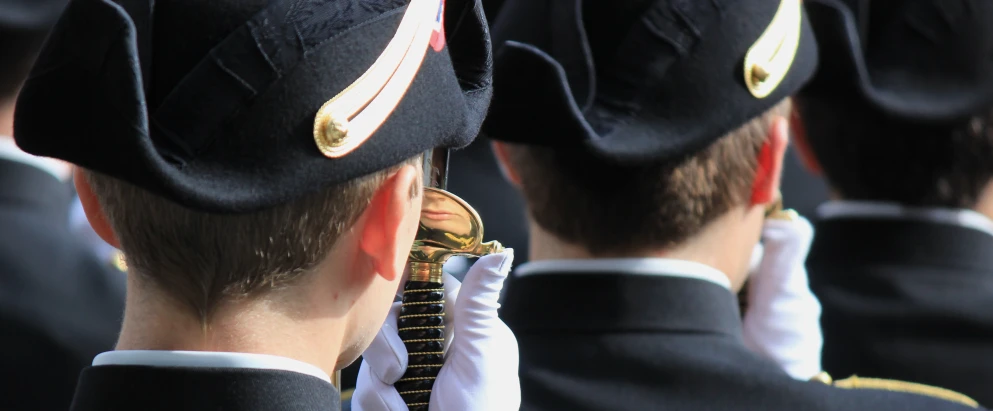 there are two men dressed in the same uniform, and one is wearing a gold - broach and another one with two other men