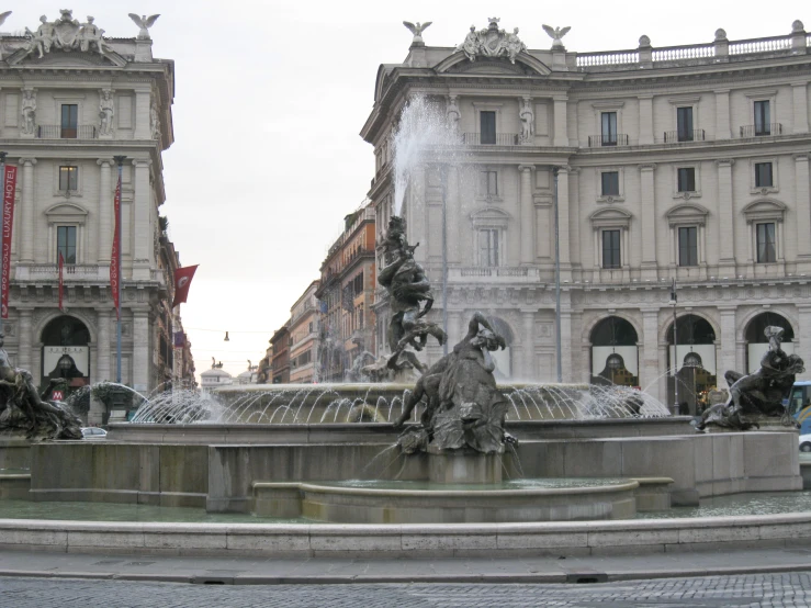 a fountain with fountains in the middle of it surrounded by tall buildings