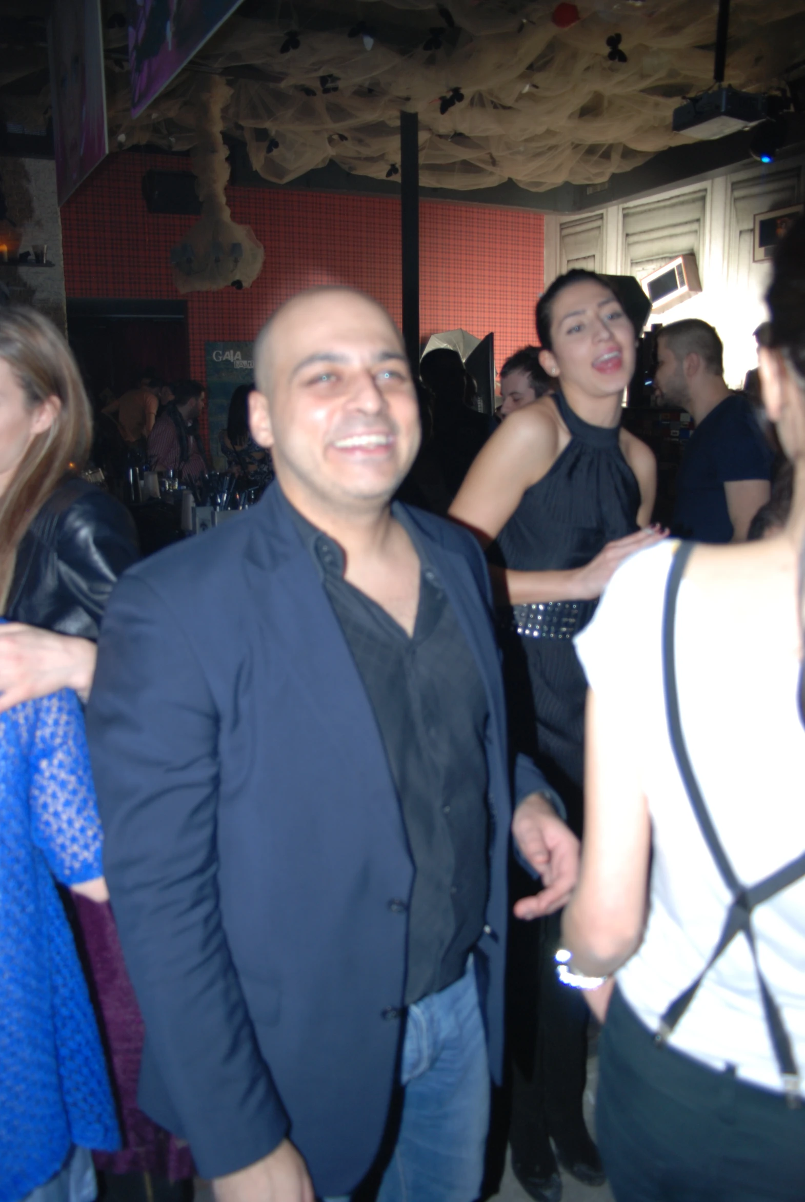 a smiling man stands in a crowded bar