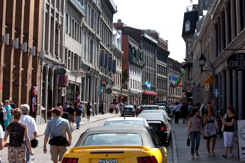 many people are walking and some cars driving down the street