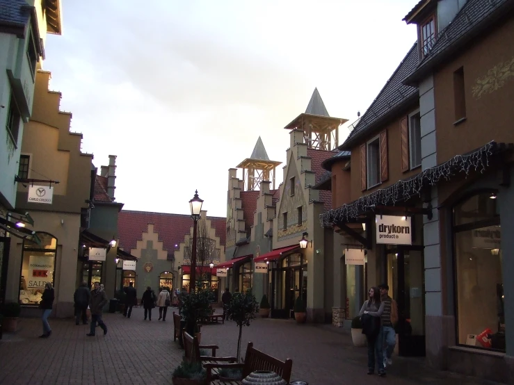 a city street with a few shops on one side and a tower in the background