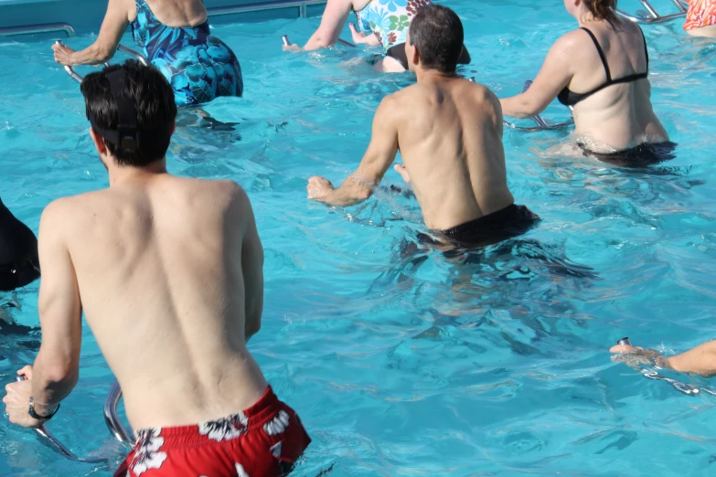 a man wearing red trunks sitting in the middle of a swimming pool