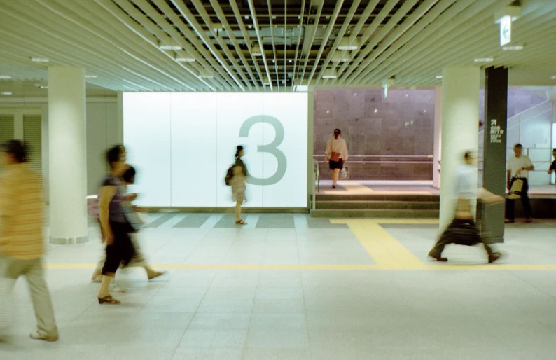 people walking through an empty building with a huge sign