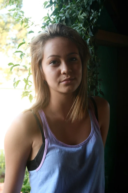 a woman stands by a bush with leaves on it