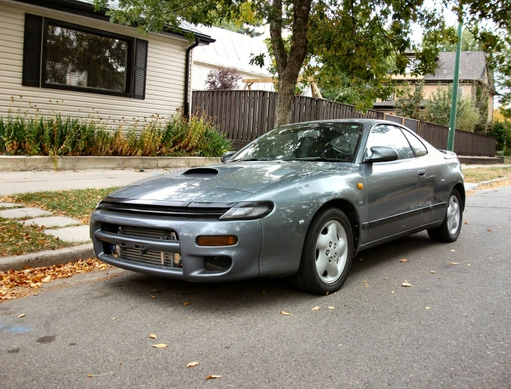 a silver car sits in front of a house