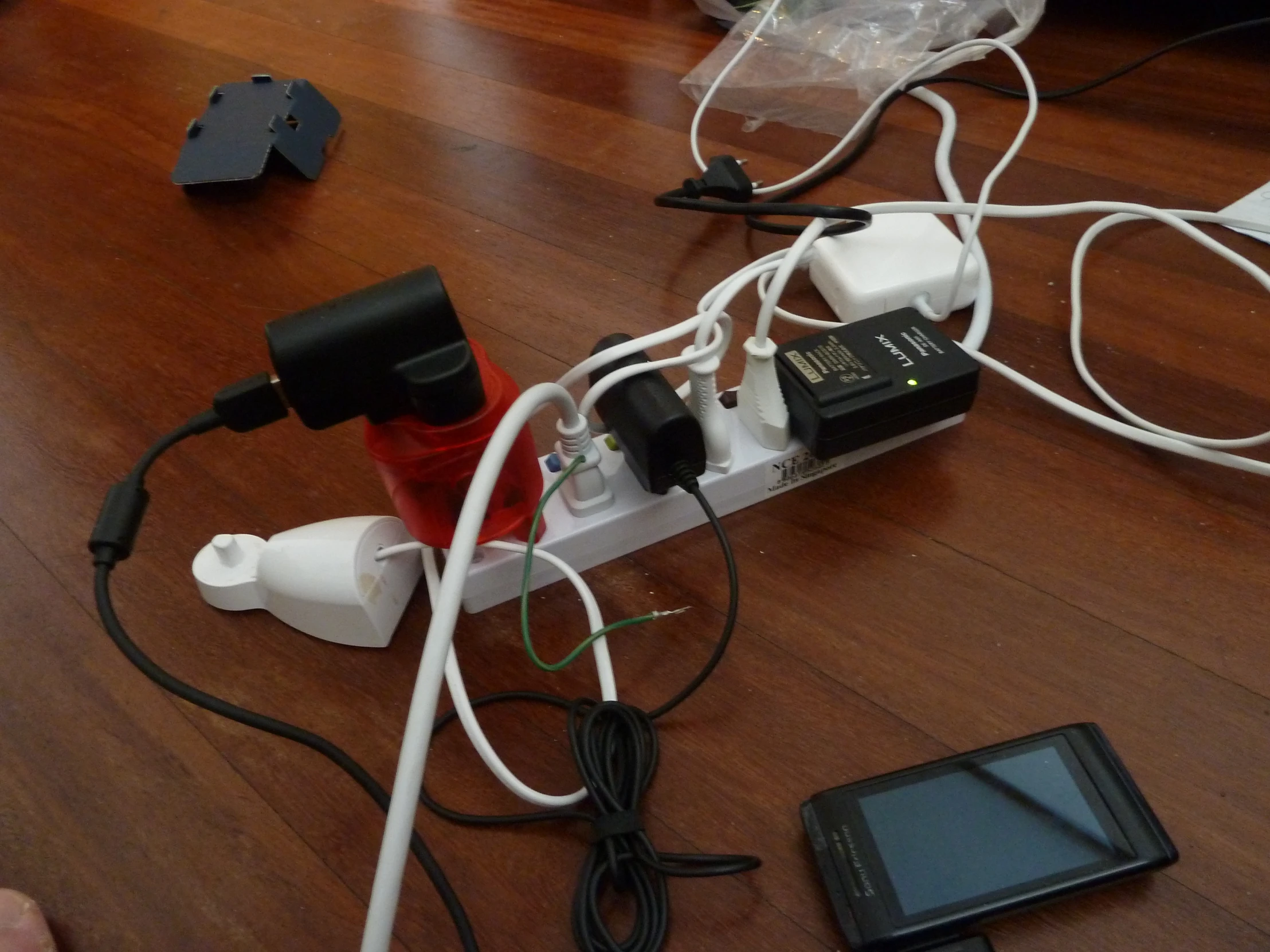 a device on the table with cords, a cellphone, and other items