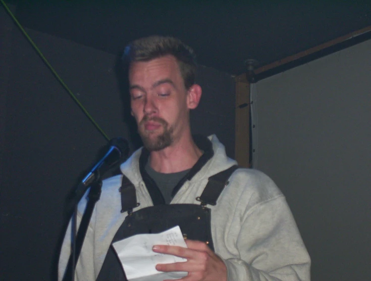 a man holding a piece of paper standing next to a microphone