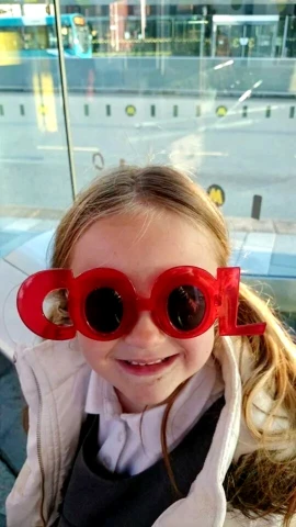 little girl with two red pairs of glasses on her face