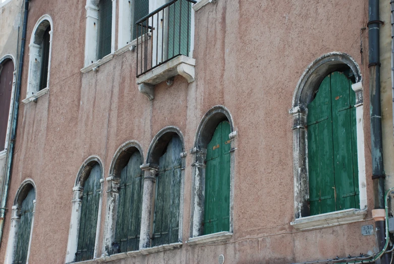 an old building has shutters and green doors