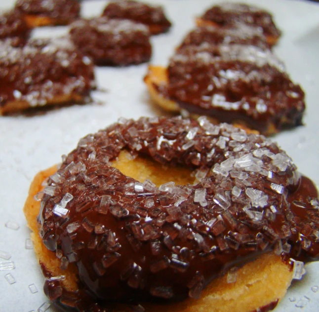 chocolate covered donuts sit on a cooling tray