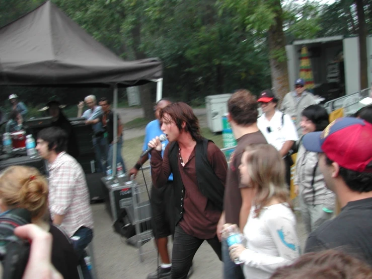 a group of people at an outdoor concert with a singer