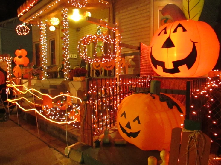 pumpkins, jack o lanternes, and decorations lit up on the outside of a house