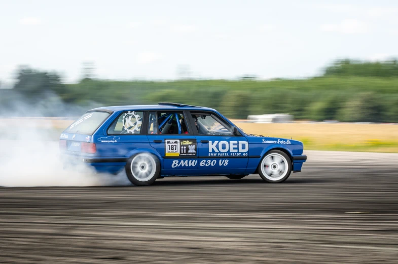 a blue hatchback car blowing out some smoke