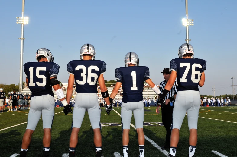 a football game with four players facing away from the camera