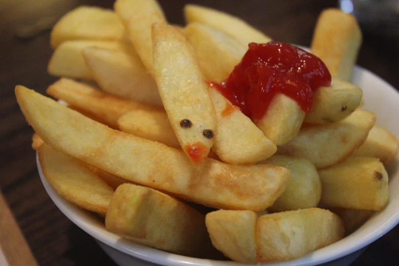 fries with ketchup sitting in a white bowl