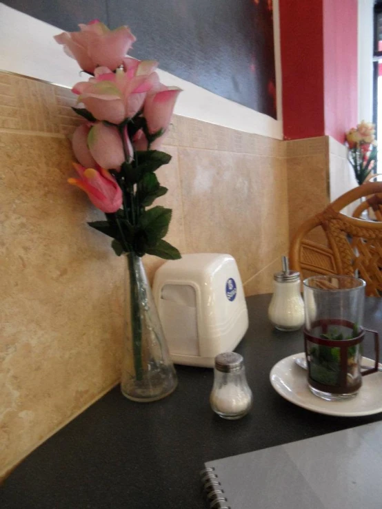 a table with coffee cups, a small plate with flower vases and a plant