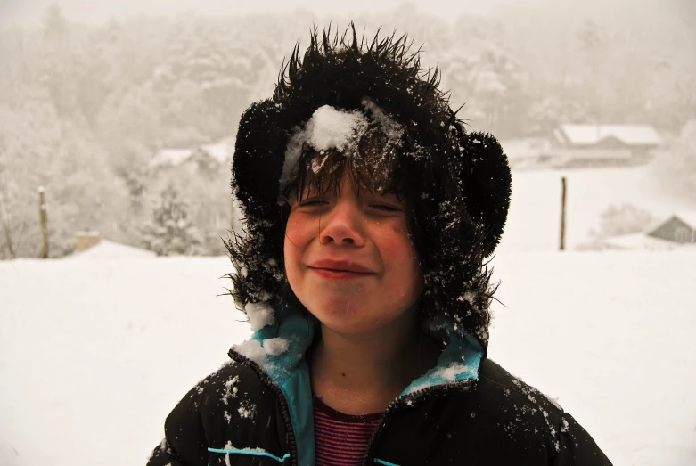 a young child in the snow with a lot of white stuff on his head