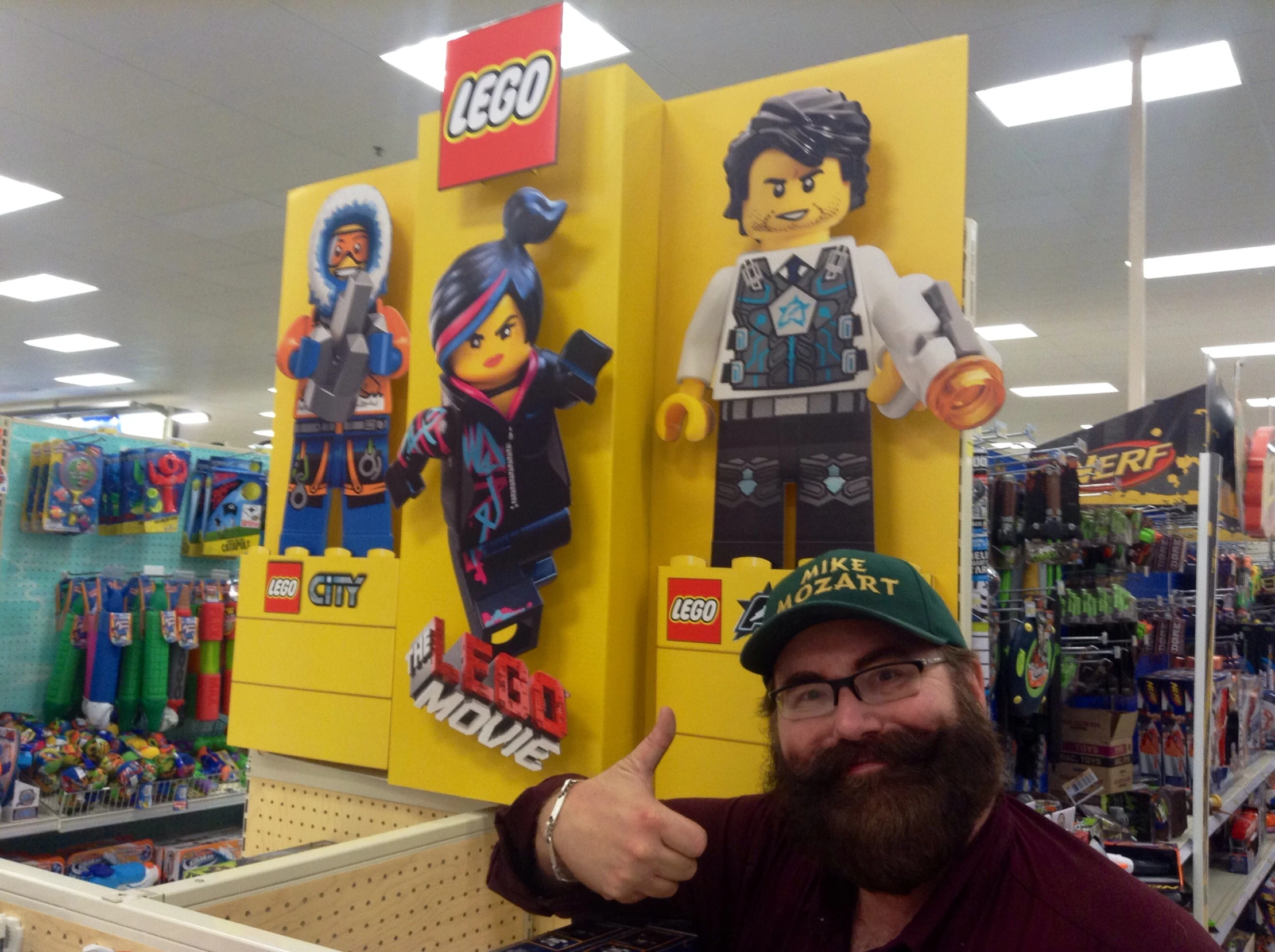 man with a lego display in the store giving thumbs up