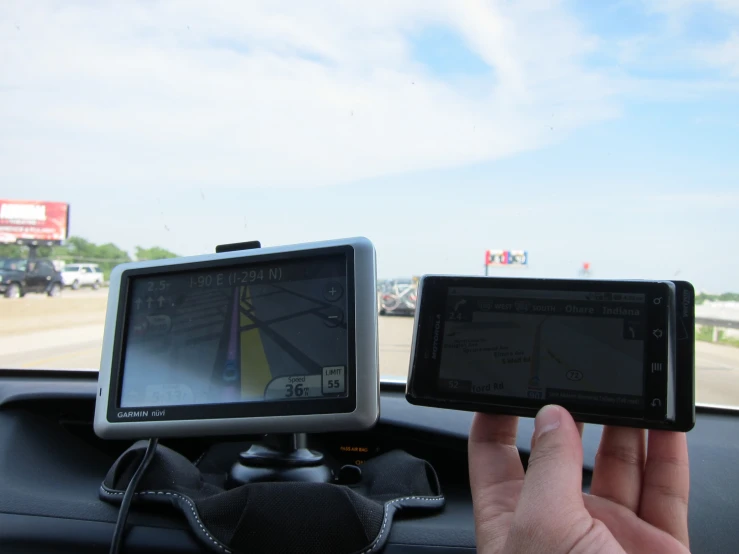 a pair of hands holding up phones in a vehicle