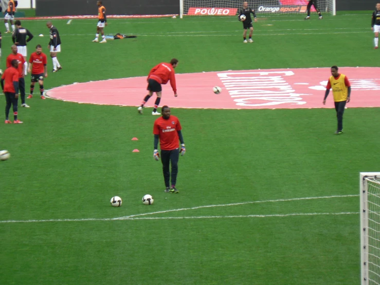 two men play with some soccer balls on a field