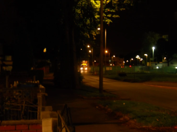 an illuminated park in the middle of a street at night