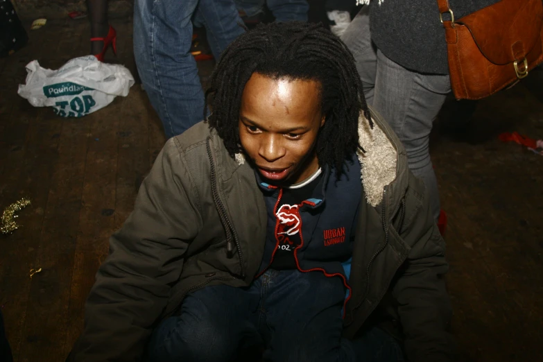 a black man with dreadlocks and no makeup, sitting down