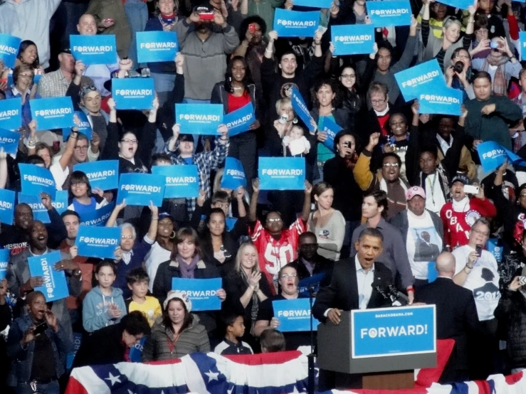 a crowd of people standing around each other holding blue signs