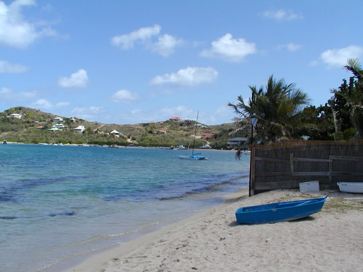 a blue canoe is on the beach in front of the water