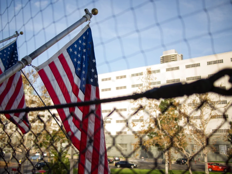 two american flags on fence, and buildings in background