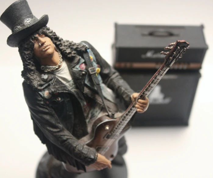 a toy man in a black hat and suit plays guitar