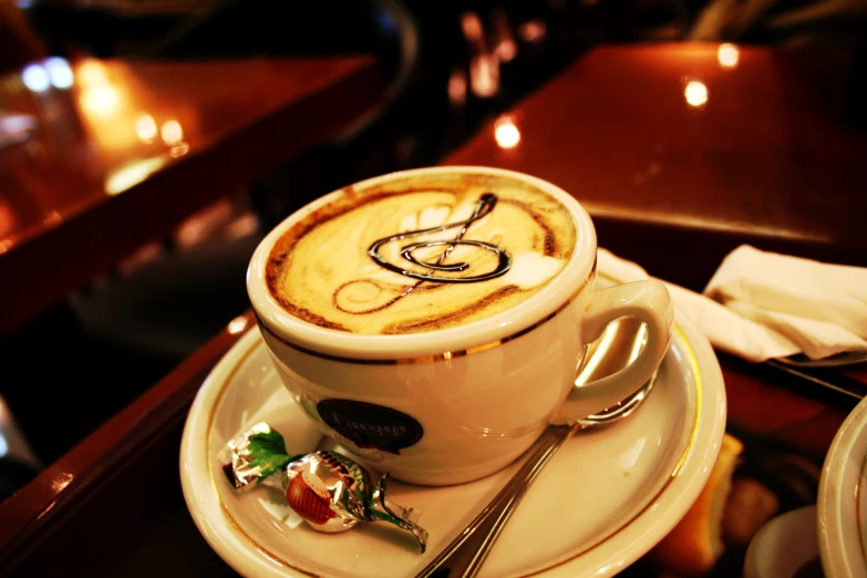 a cappuccino with whipped cream in a cup with an alphabet sign drawn on it