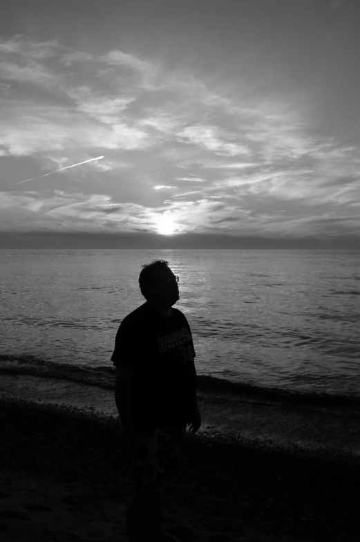 a man standing on top of a beach next to the ocean