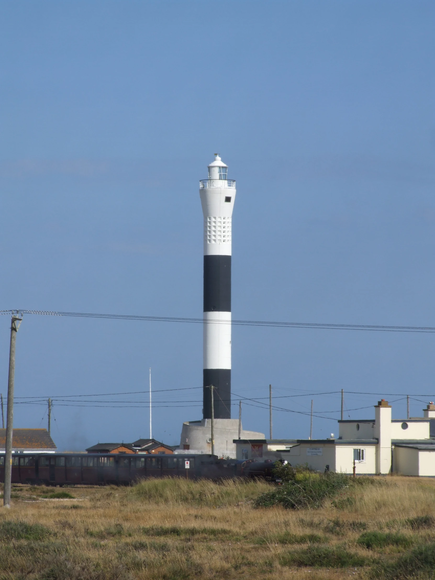 there is a small white and black lighthouse next to the road