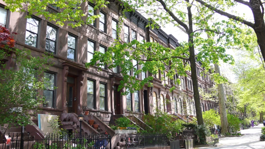 a tall brick building with trees on the sidewalk