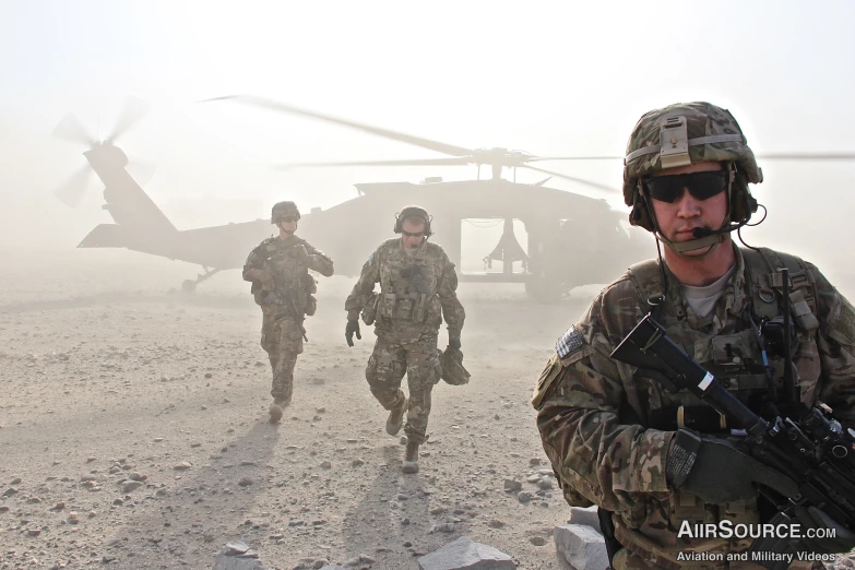 a group of people in uniform walking by an helicopter