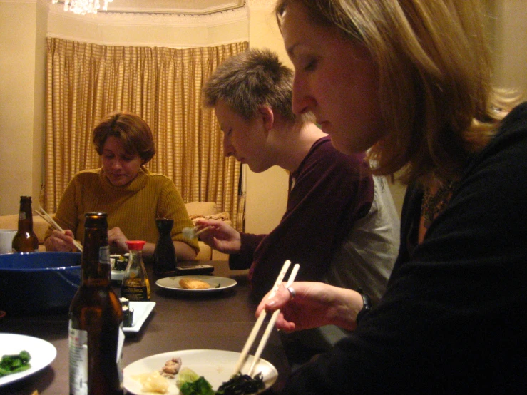 group of people eating at a table with chopsticks