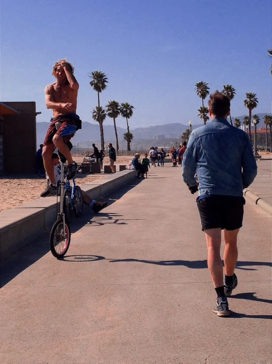 a man rides a bike near a street with palm trees