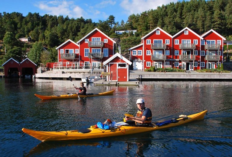 a couple of kayakers are out on the water near houses