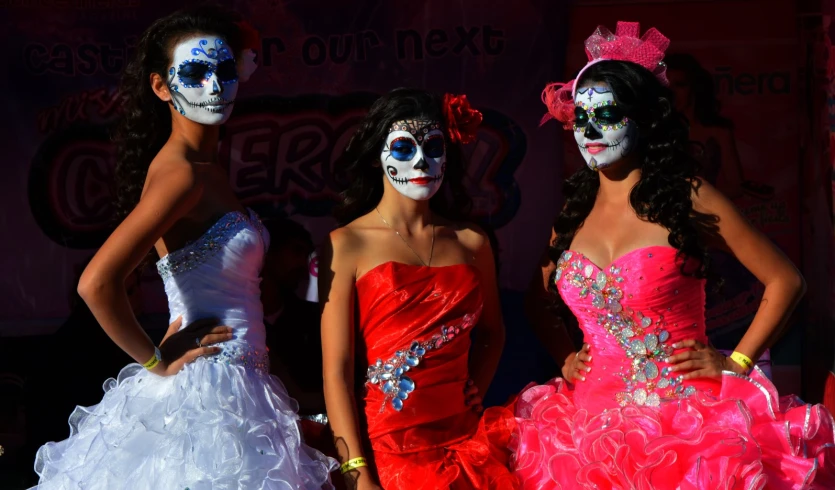 three young women dressed in masks and dresses