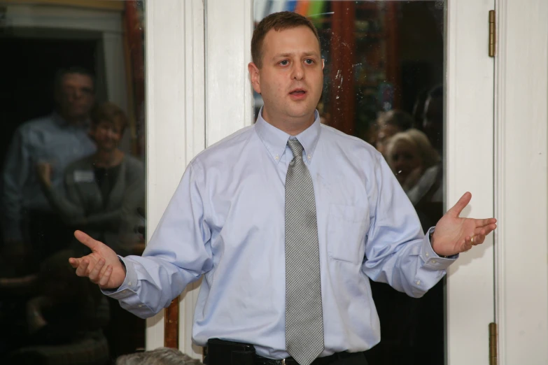 a man with a tie and an open hand on his hip