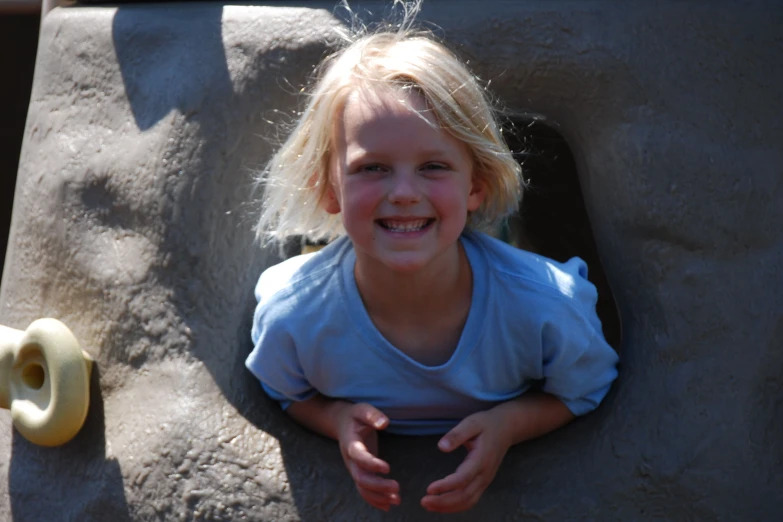 a small blonde child is sitting on a large rock