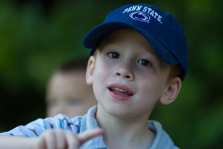 the boy wearing a blue hat is pointing to the side