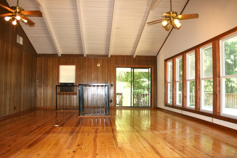 a empty room with wooden floors and ceiling fan