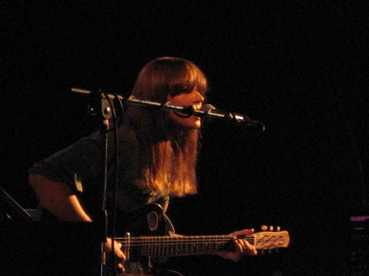 a girl is playing a guitar on stage