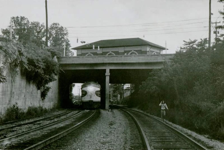 the entrance to a tunnel beneath a bridge over railroad tracks