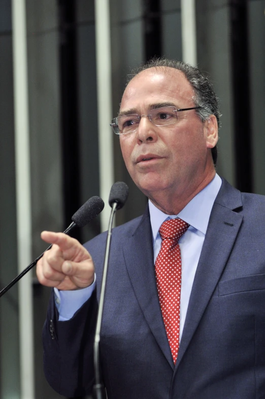 man in suit speaking with microphone in front of him