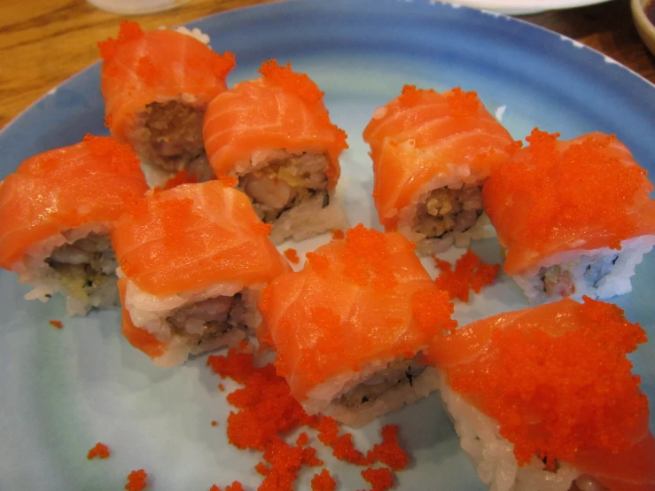 a blue plate with sushi on it, covered in sauce