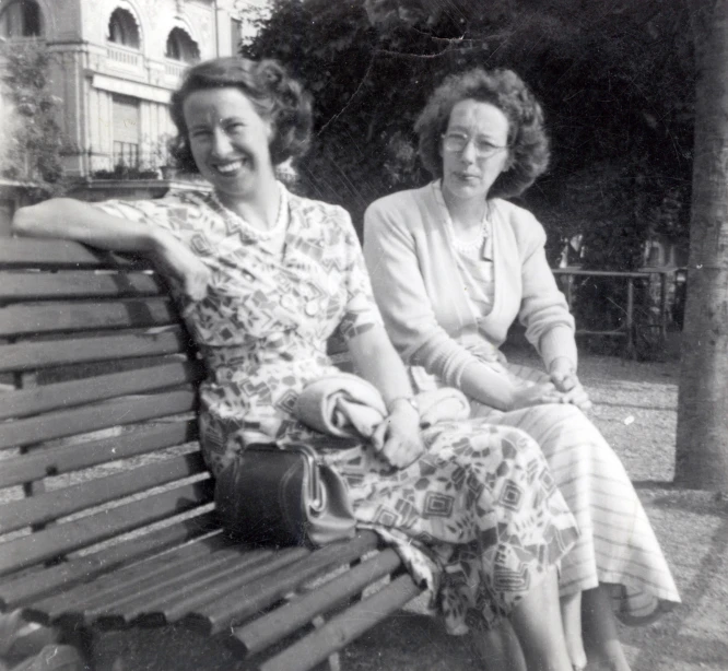 two women sit on a bench and smile