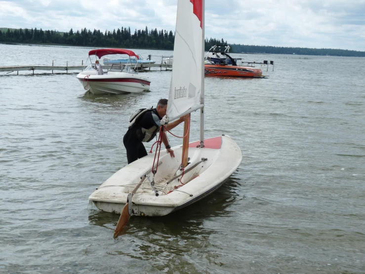 man on a sailboat holding the mast